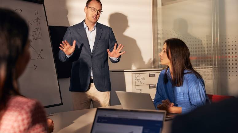 Pracownik prezentuje wyniki na spotkaniu z zespołem.