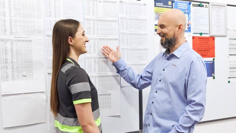 Kierownik sekcji w magazynie omawia plan pracy z pracownikami magazynu